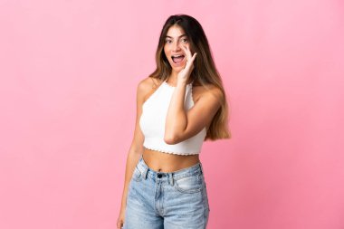 Pembe arka planda izole edilmiş genç beyaz kadın ağzı açık bağırıyor.