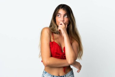 Beyaz arka planda izole edilmiş genç beyaz bir kadın. Şüpheleri var ve kafası karışmış bir yüz ifadesi var.