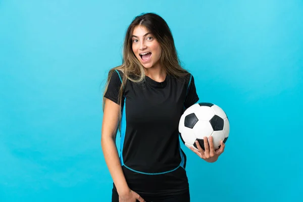 若いサッカー選手の女性は驚きの表情で青の背景に隔離されました — ストック写真