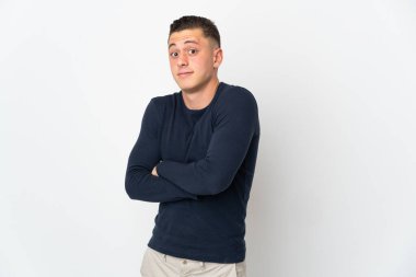 Beyaz arka planda izole olmuş genç beyaz bir adam omuzlarını kaldırırken şüpheyle hareket ediyor.