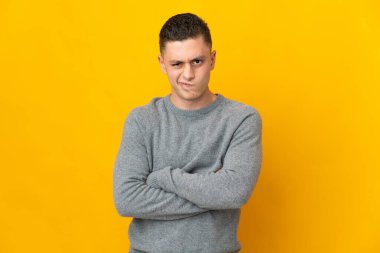 Mutsuz bir ifadeyle sarı arka planda izole edilmiş genç beyaz bir adam.