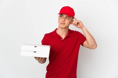 İş üniformalı bir pizzacı beyaz arka planda izole edilmiş pizza kutularını alıyor. Şüpheleri var ve düşünüyor.