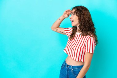 Mavi arka planda kıvırcık saçlı genç bir kadın.