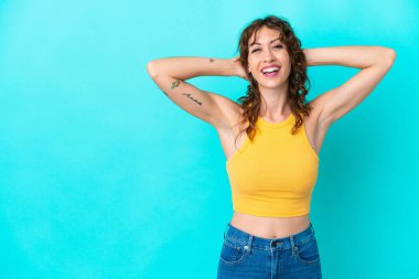 Kıvırcık saçlı genç bir kadın mavi arka planda yalnız gülüyor.