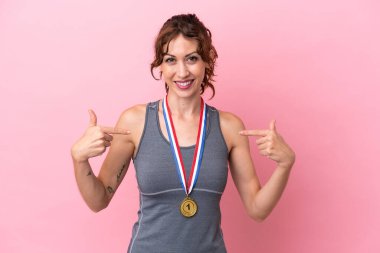 Pembe arka planda madalyalı, gururlu ve kendini beğenmiş beyaz bir kadın.