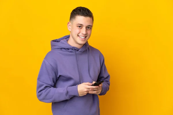 Молодой Кавказский Человек Изолирован Желтом Фоне Отправляя Сообщение Мобильником — стоковое фото