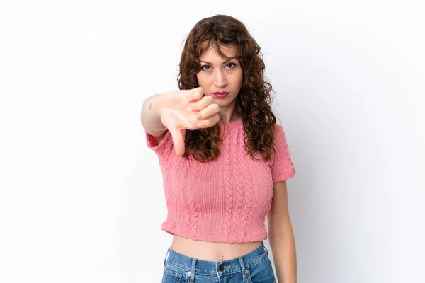 白い背景に孤立した巻き毛の若い女性が否定的な表情で親指を下に示す — ストック写真