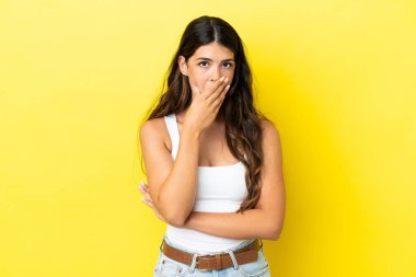 Sarı arka planda izole edilmiş genç beyaz kadın sağa bakarken şaşırdı ve şok oldu.