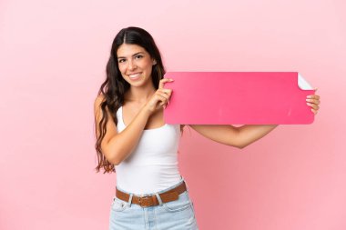 Pembe arka planda izole edilmiş beyaz bir kadın boş bir pankart tutuyor.