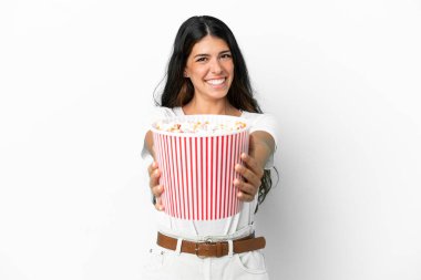 Beyaz arka planda izole edilmiş beyaz bir kadın elinde koca bir kova patlamış mısır tutuyor.