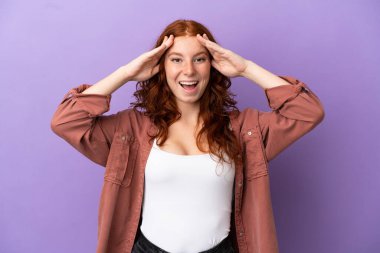 İzole edilmiş mor arkaplanı olan genç kızıl saçlı kız. Sürpriz bir ifadeyle.