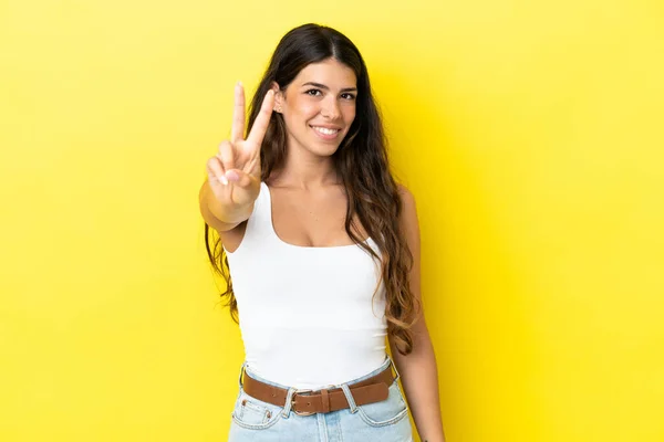 Νεαρή Καυκάσια Γυναίκα Απομονωμένη Κίτρινο Φόντο Χαμογελώντας Και Δείχνοντας Σύμβολο — Φωτογραφία Αρχείου