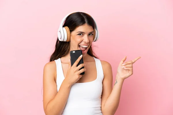 Νεαρή Καυκάσια Γυναίκα Απομονωμένη Ροζ Φόντο Ακούγοντας Μουσική Κινητό Και — Φωτογραφία Αρχείου