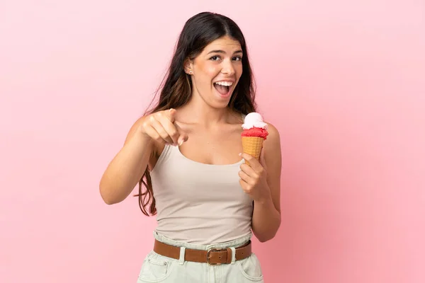 若いですCaucasian女性とともにCornetアイスクリーム孤立オンピンク背景驚きと指摘フロント — ストック写真