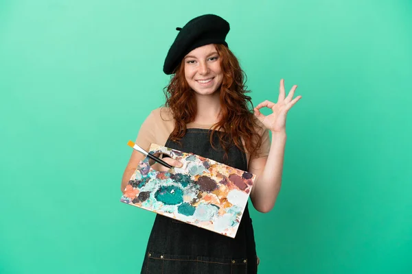 Nastoletni Rudowłosy Artysta Trzymając Paletę Izolowane Zielonym Tle Pokazując Znak — Zdjęcie stockowe