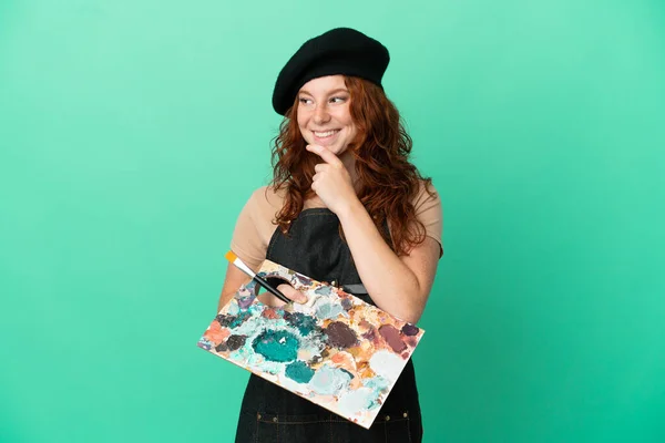Teenager Redhead Artist Holding Palette Isolated Green Background Looking Side — Stock Photo, Image