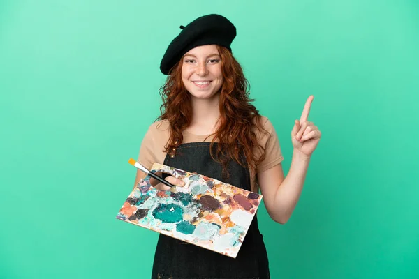 Teenager Redhead Artist Holding Palette Isolated Green Background Pointing Great — Stock Photo, Image