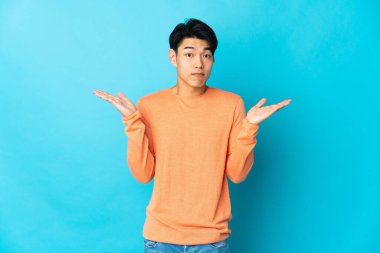 Mavi arka planda izole edilmiş genç bir Çinli şüpheli hareketler yapıyor.