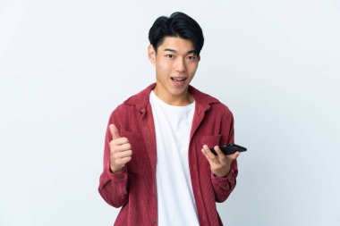 Genç Çinli adam beyaz arka planda izole edildi. Cep telefonuyla onay veriyor.