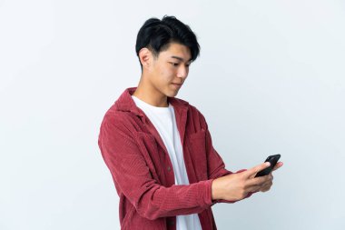 Beyaz arka planda izole edilmiş genç bir Çinli cep telefonuyla mesaj ya da e-posta gönderiyor.