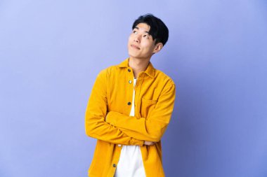 Mor arka planda izole edilmiş genç bir Çinli gülümserken yukarı bakıyor.