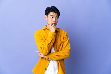 Mor arka planda izole edilmiş genç bir Çinli gergin ve korkmuş.