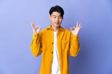 Mor arka planda Zen pozu almış genç bir Çinli.