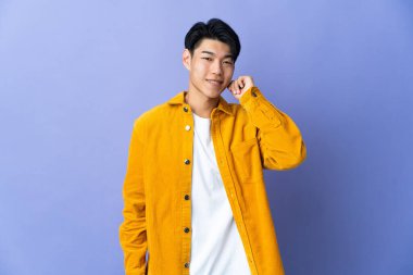 Mor arka planda yalnız yaşayan genç bir Çinli gülüyor.