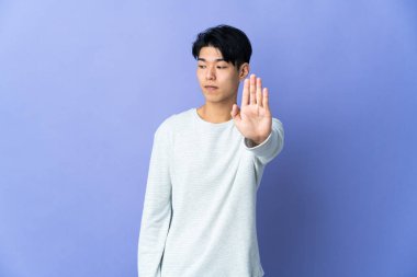 Mor arka planda izole edilmiş genç bir Çinli dur hareketi yapıyor ve hayal kırıklığına uğruyor.