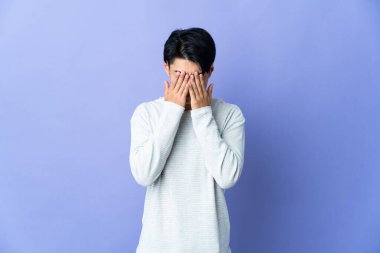 Genç Çinli adam mor arka planda izole edilmiş, yorgun ve hasta bir ifadeyle.