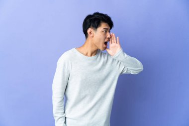 Mor arka planda izole edilmiş genç bir Çinli ağzı sonuna kadar açık bağırıyor.