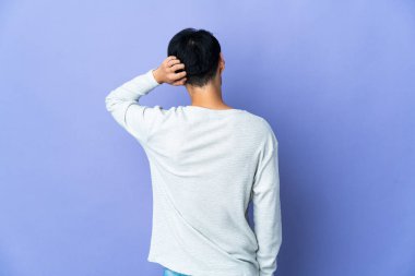 Genç Çinli bir adam mor arka planda izole edilmiş ve düşünüyor.