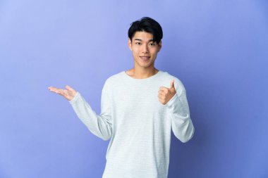 Mor arka planda izole edilmiş genç bir Çinli avucunun içinde bir ilan vermek için hayali bir mekan tutuyor.