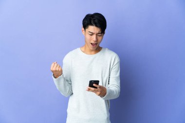 Mor arka planda izole edilmiş genç Çinli bir adam şaşırdı ve bir mesaj gönderiyor.