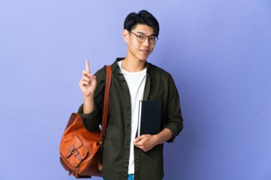 Mor arka planda izole edilmiş genç bir bayan en iyinin işareti olarak parmağını kaldırıyor.