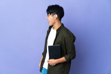 Mor arka planda izole olmuş genç bir bayan. Yan pozisyonda gülüyor.