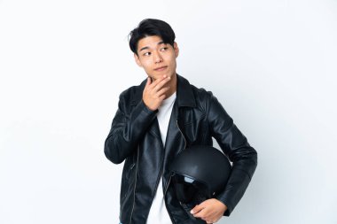 Motosiklet kasklı Çinli bir adam beyaz arka planda izole edilmiş gülümserken yukarı bakıyor.