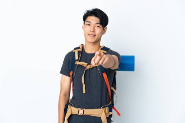 Dağcı Çinli adam beyaz arka planda izole edilmiş, mutlu bir ifadeyle ön tarafı işaret ediyor.