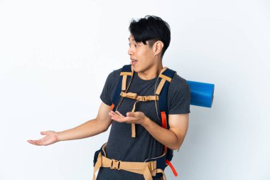 Dağcı Çinli adam, beyaz arka planda izole edilmiş, sürpriz bir ifadeyle yan tarafa bakıyor.