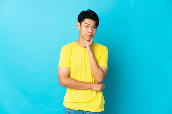 青い背景と思考で隔離された若い中国人男性 — ストック写真