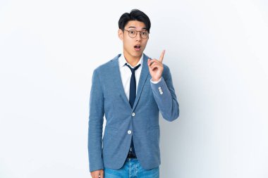 Genç Çinli iş adamı beyaz arka planda izole edildi. Çözümün farkına varmak için parmağını kaldırdı.