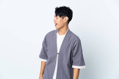 Beyaz arka planda yalnız yaşayan genç bir Çinli yan yana gülerek...