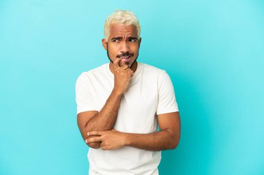 Genç Kolombiyalı yakışıklı adam mavi arka planda izole edilmiş gergin ve korkmuş.