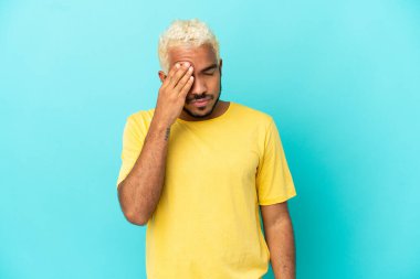 Genç Kolombiyalı yakışıklı adam mavi arka planda başağrısı ile izole