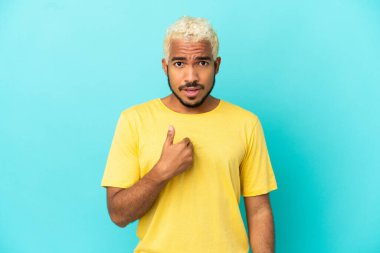 Genç Kolombiyalı yakışıklı adam mavi arka planda izole edilmiş kendini işaret ediyor.