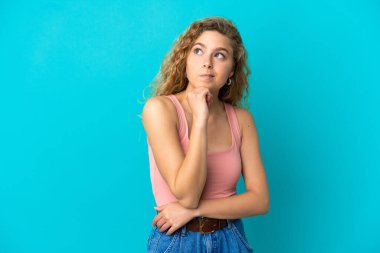 Genç sarışın kadın mavi arka planda izole edilmiş ve yukarı bakıyor.