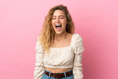Pembe arka planda izole edilmiş genç sarışın kadın ağzı açık bağırıyor.