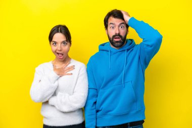 Sarı arka planda, şaşırtıcı bir yüz ifadesi olan genç, beyaz bir çift.