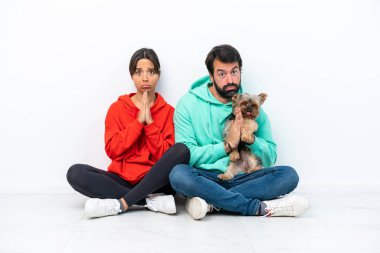 Beyaz arka planda izole edilmiş evcil hayvanlarıyla yerde oturan beyaz bir çift