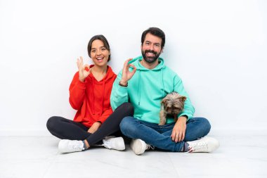 Beyaz arka planda izole edilmiş evcil hayvanlarıyla yerde oturan beyaz bir çift parmaklarıyla 